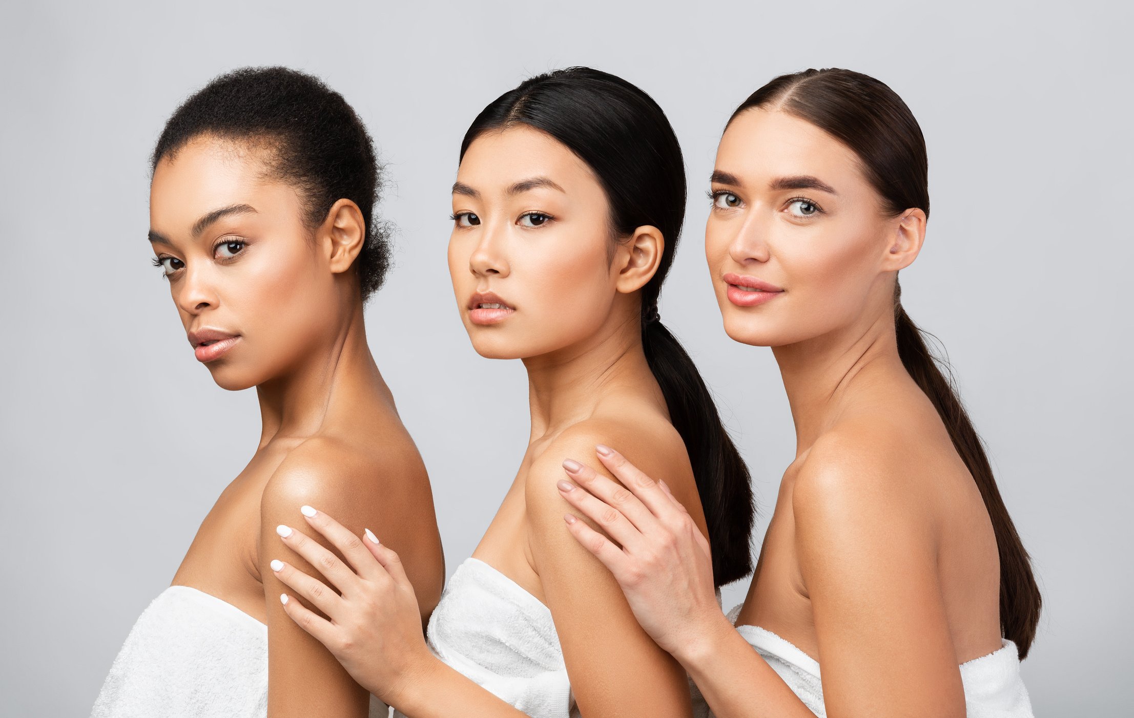 Three Diverse Women In Bath Towels Posing Over Gray Background