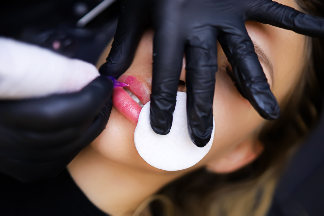 The Tattoo Artist Presses a Cotton Sponge to the Client's Lip so